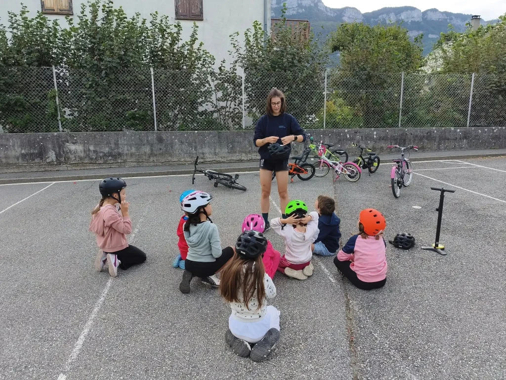 Des enfants écoutant un adulte leur faire de la prévention sur le casque en vélo